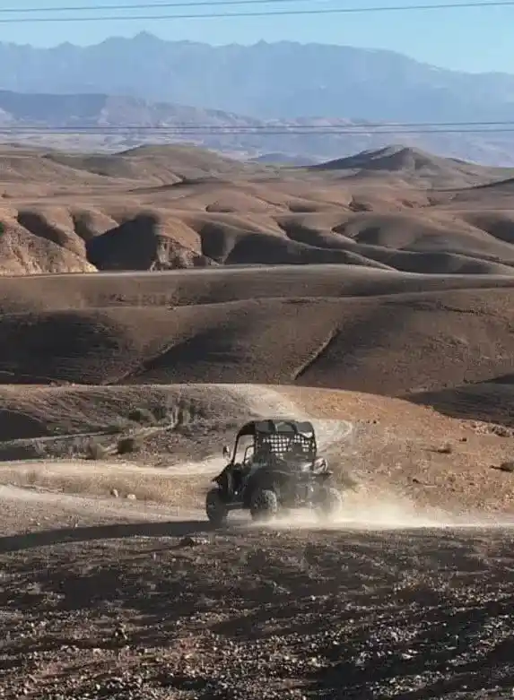 Buggy crossing the rocky hills of Agafay Desert with Atlas Mountains views near Marrakech