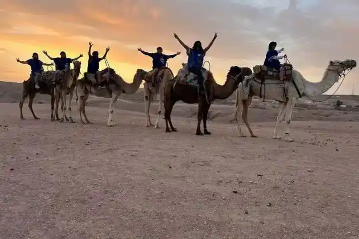 Travelers posing on camels during a sunset ride in the Agafay Desert near Marrakech