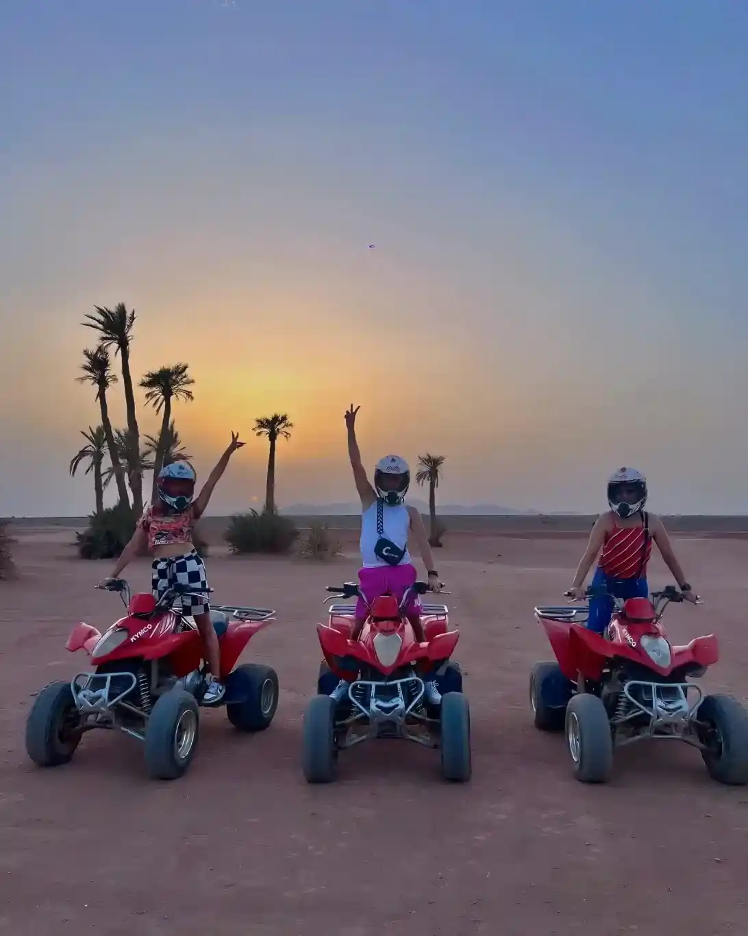 Family enjoying a sunset quad bike ride in Marrakech Palmeraie desert with palm trees in the background.