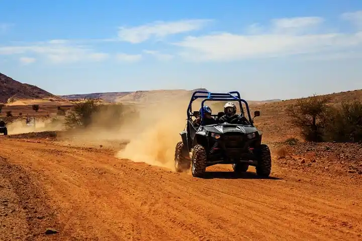 Off-road buggy driving on a desert track in Agafay near Marrakech raising dust