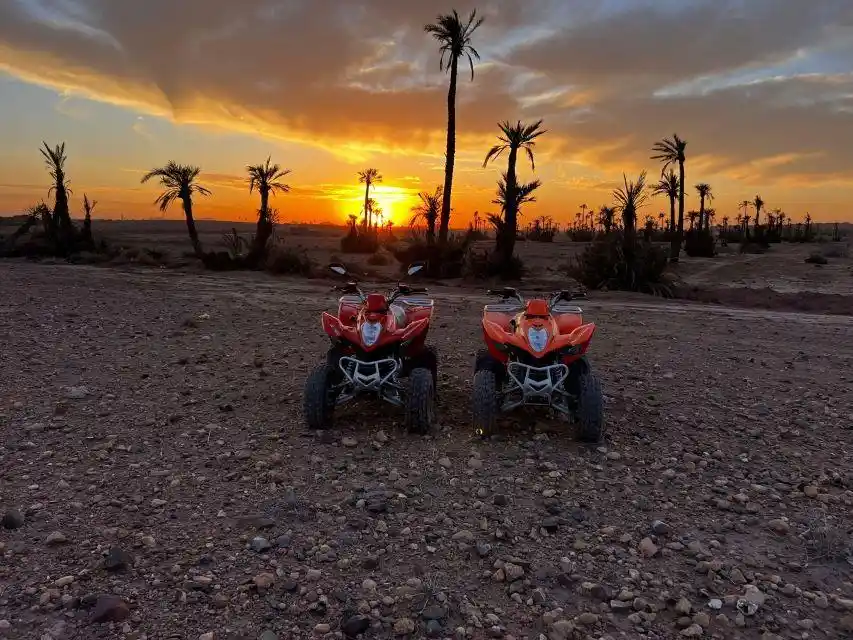 Quad bikes parked in front of a spectacular sunset in Marrakech Palmeraie desert landscape.