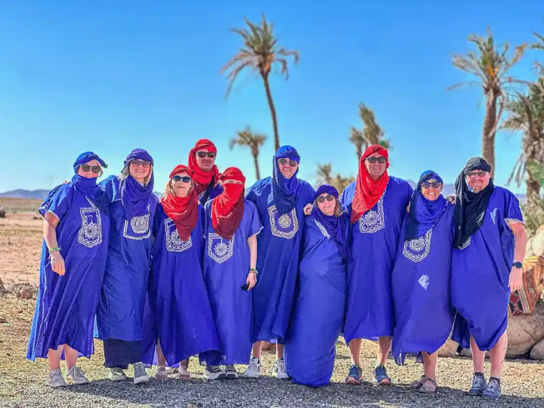 Tourists wearing traditional Moroccan blue robes during a quad biking and camel ride tour in Marrakech