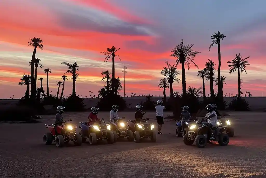 Group of riders on quad bikes during a sunset tour in Marrakech Palmeraie with colorful evening sky and palm trees.