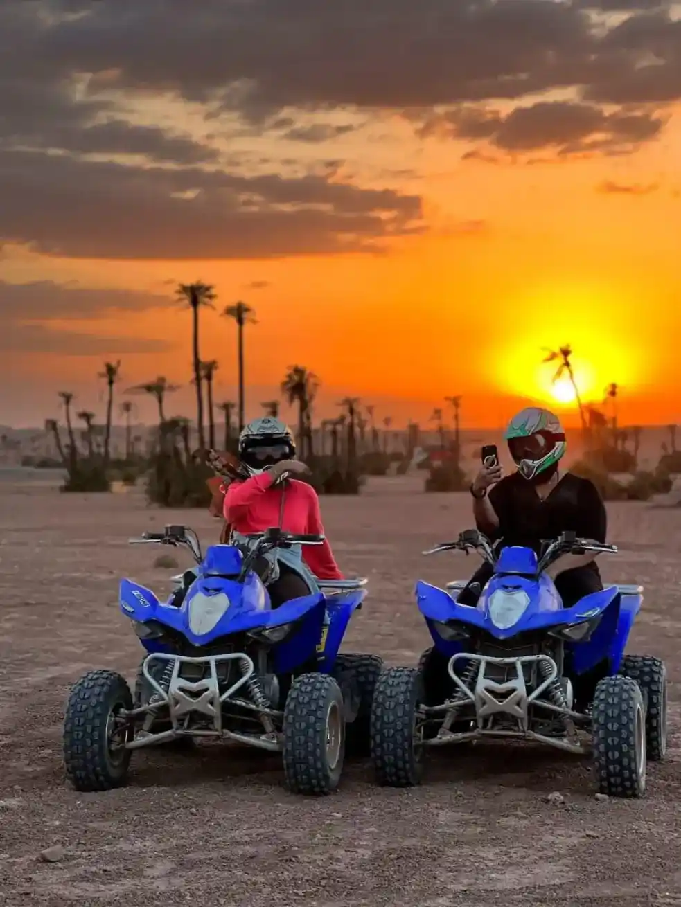 Two riders enjoying a sunset quad biking tour in Marrakech with palm trees in the background